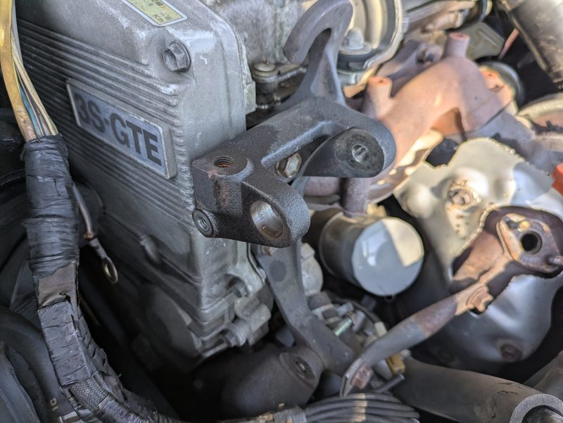 トヨタセリカST165の3S-GTEエンジン横。オルタネーターブラケットからフランジ付きブッシュを叩き抜いた状態。